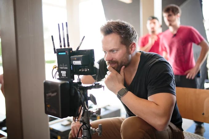 Focused cameraman adjusts professional video equipment on film set