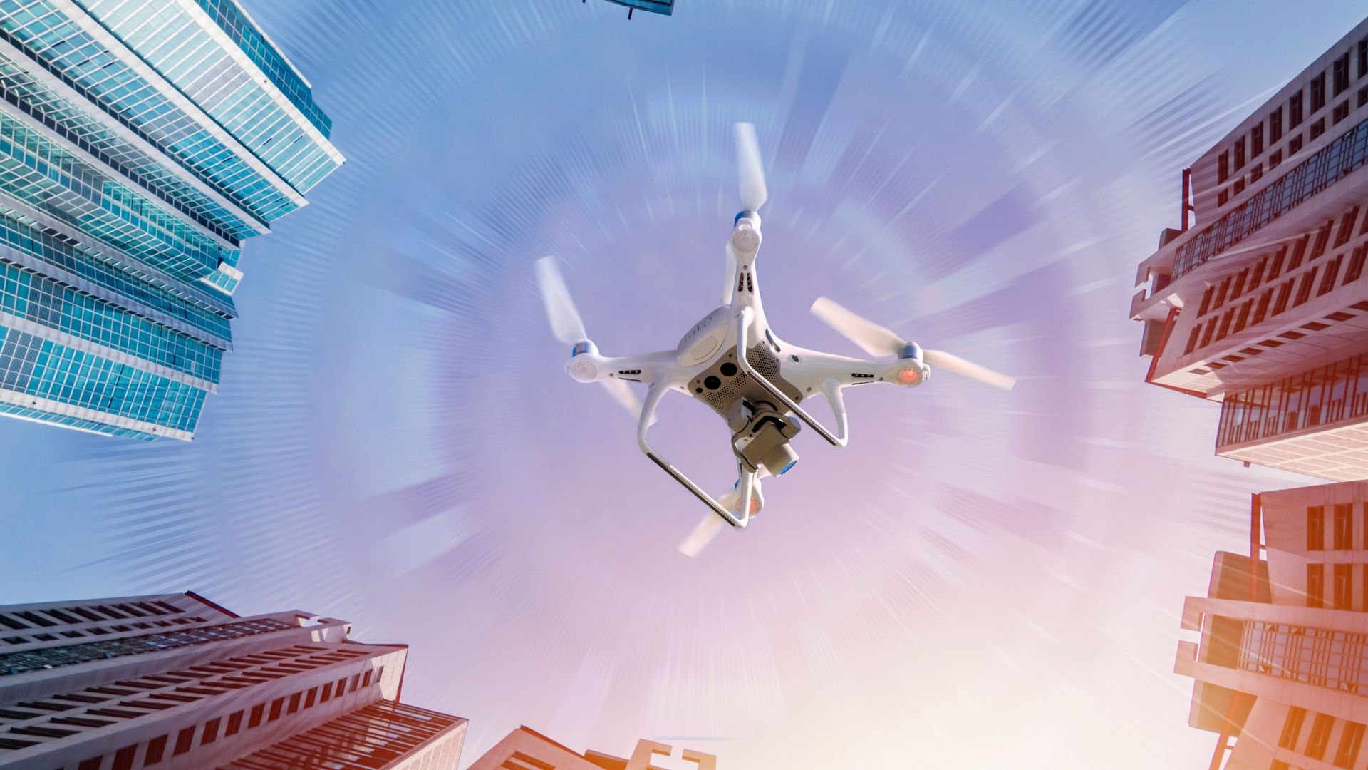 White drone flying between modern skyscrapers with blurred motion effect