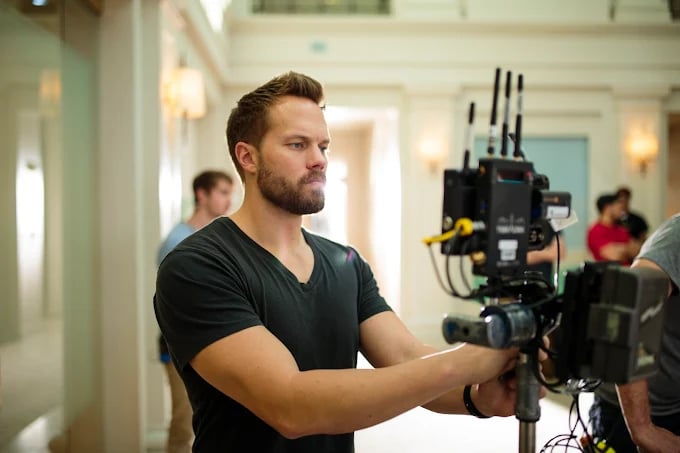 Cameraman operating professional video camera on set in bright interior