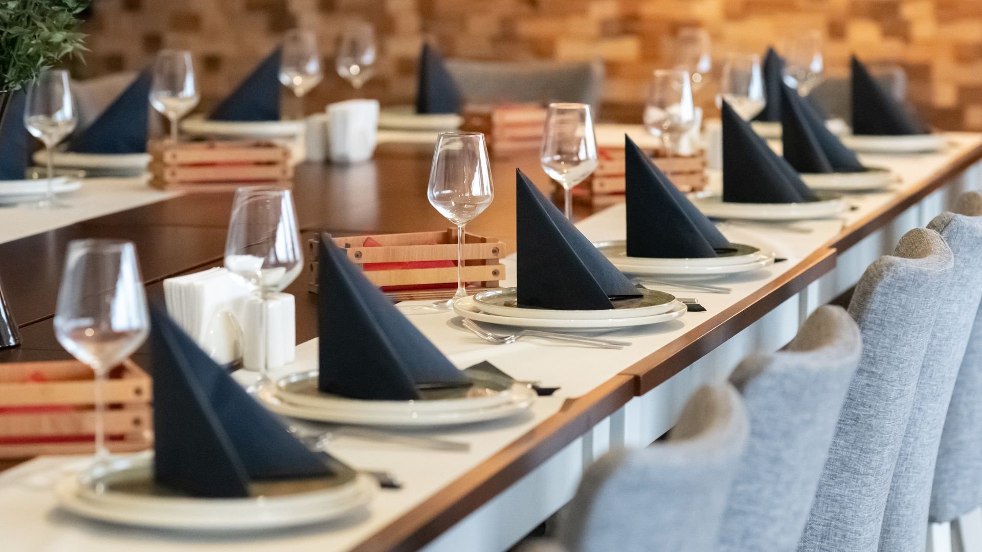 Elegantly set dining table with navy napkins, wine glasses, and wooden decor