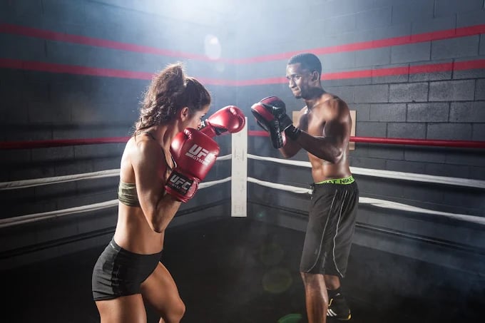 Two boxers facing off in a boxing ring with red gloves and ropes