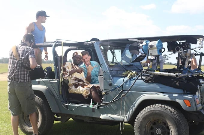 Film crew working on location with Jeep in grassy field