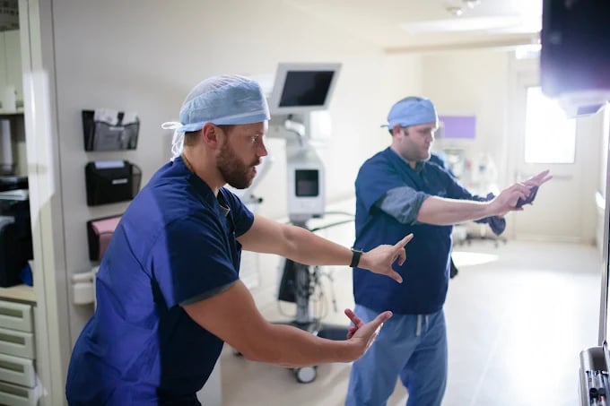 Medical staff in blue scrubs communicating in a hospital operating room