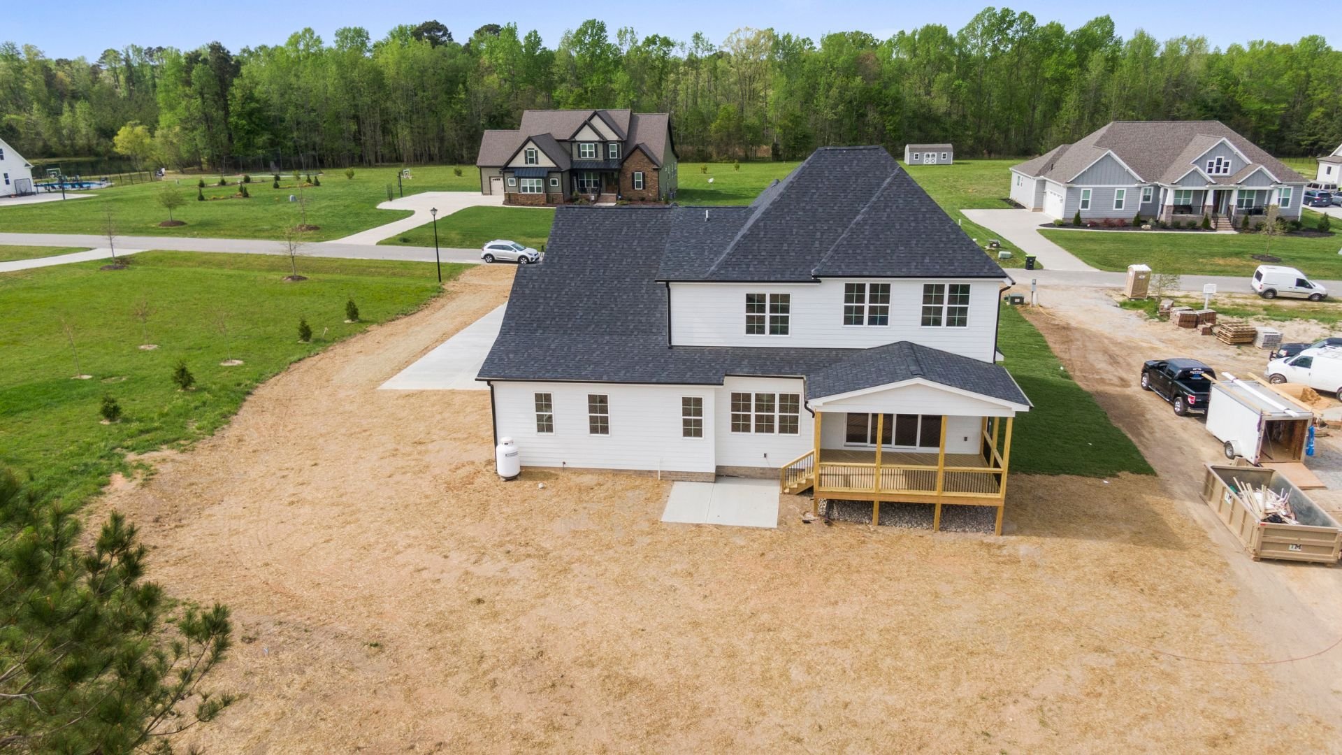 Aerial view of new construction white house with wooden deck in suburban neighborhood