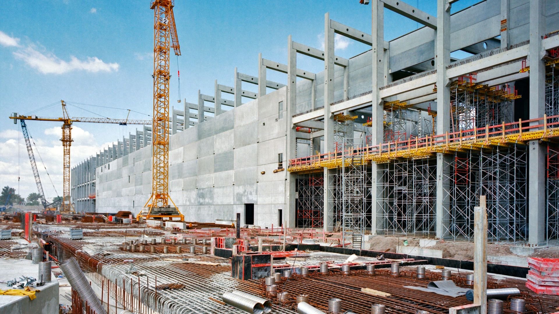 Large construction site with cranes, scaffolding, and concrete structure in progress